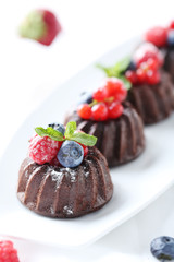 Sweet chocolate cakes with berries on white wooden table