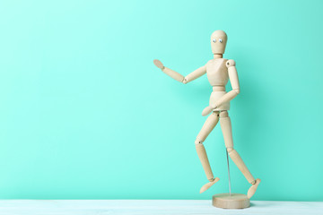 Wooden figure with googly eyes on a green background