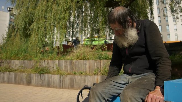 old man, poor man, sad elderly man sitting alone in a city park 