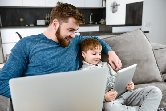 Happy father using laptop while his son look at tablet