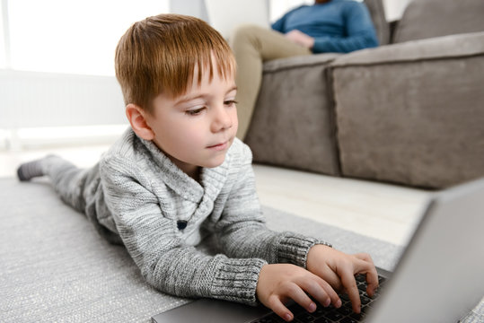 Little cute child using laptop while lies in floor