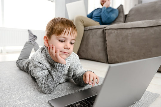 Cheerful child using laptop while lies in floor