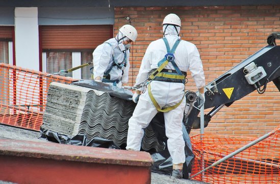 Trabajadores de amianto retiran tejado de fibrocemento con una gr&uacute;a, en Mondragon (Guipuzcoa)