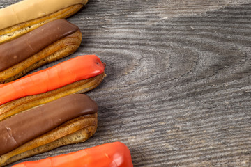 Tasty eclairs on wooden table, close up