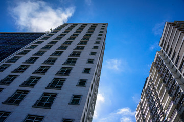 Fototapeta premium From bottom to top view of modern residential skyscrapers, high-rise buildings with palm trees and swimming pools on their roofs and blue sky, Copacabana district, Rio de Janeiro, Brazil