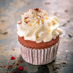 Delicious red velvet cupcake on rusty old metal background. Valentines Day greeting card concept with copy space. Retro style toned.