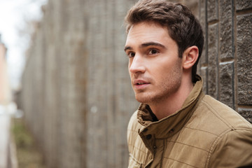 Attractive young man walking on the street and looking aside.