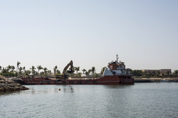 Boat dredger creating land coastline Souly Bay Salalah Oman