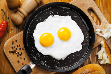 Two fried eggs in a frying pan cooked for breakfast. Delicious international meal on a table. Homemade food, top view.