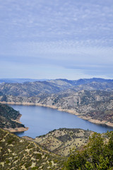 Aerial view of Lake Berryessa from the Blue Ridge Trail on a sunny day, featuring the low water levels of the reservoir, and the surrounding blue oak woodland