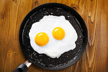 Traditional healthy easy quick breakfast meal made of two fried eggs served on a frying pan. International simple food, top view.