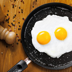 Fried eggs for delicious healthy easy breakfast on a table. Fresh homemade meal on a frying pan. Traditional breakfast food. International cuisine food.  Top view.