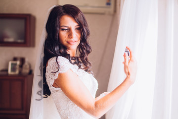 young bride with perfume is getting ready at home in the morning, wedding day 