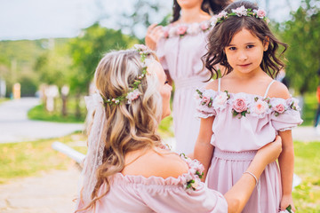 Bride with bridesmaids and little girl kids in the same color dress posing on camera in the park on the wedding day