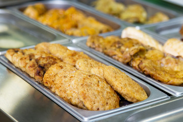cutlets and meat dishes in buffet on metal plates.
