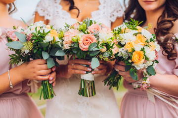 Bride with beautiful bridesmaids in lilac color dresses holding bouquets. Autumn in the Park. Sunny...