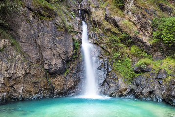 Fototapeta na wymiar Chock Ka Din Waterfall Medium is beautiful , emerald green water and the people who want to relax on the hill in Kanchanaburi in Asia.