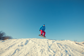 Snowboarder jumping on background of blue sky