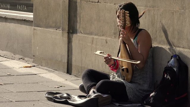 playing music in the street: street artist playing string instrument 