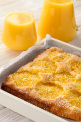 Orange cake and orange juice on white wooden background.