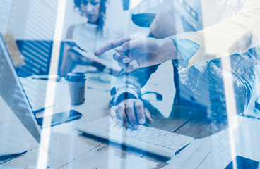 Double exposure concept.Group of coworkers working together in a sunny studio.Man typing on computer keyboard at wood table.Skyscraper office building blurred background.Horizontal.
