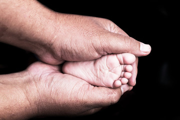 Small feet baby holds his father in he hands