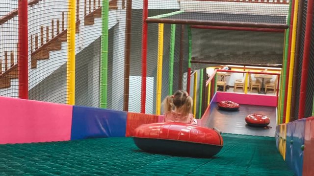 the little girl on the tubing rolls with slides in the play area