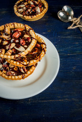 Mini tarts with nuts and caramel on a rustic background, top view, copy space 