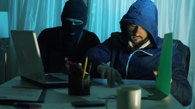 two thief hacker working on laptop in the night stealing data