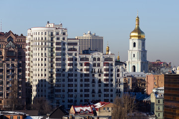Urban contrasts of the city of Kiev. Modern residential buildings and bell tower of St. Sophia Cathedral.