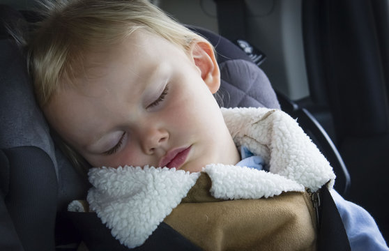 horizontal close up image of a little caucasian female toddler sound asleep in her carseat in the car.
