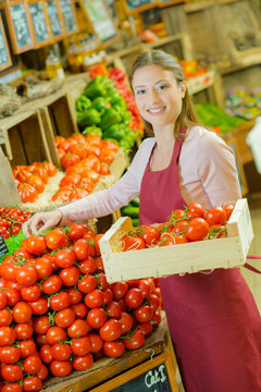 Shop assistant piling up tomatoes