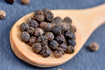 Wooden spoon with black peppercorns