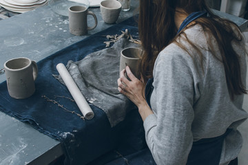 Female potter working with clay in a ceramics workshop, back view