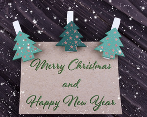 Christmas Xmas New Year greeting card with three Christmas tree on clothespins on dark wooden background