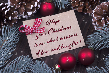 Christmas Xmas New Year Holiday greeting card with Christmas balls bell ribbon fir branches cones and text Hope your Chrismas is an ideal mesure of fun and laugfter