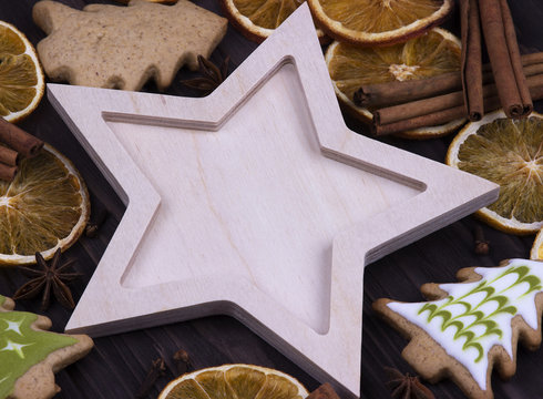Christmas Xmas New Year Holiday greeting card with empty wooden star cones star anice cinnamone dried oranges Christmas tree cookies on dark wooden background, space for text