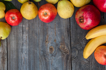 Ripe fruits lined frame on a gray wooden surface, empty space in