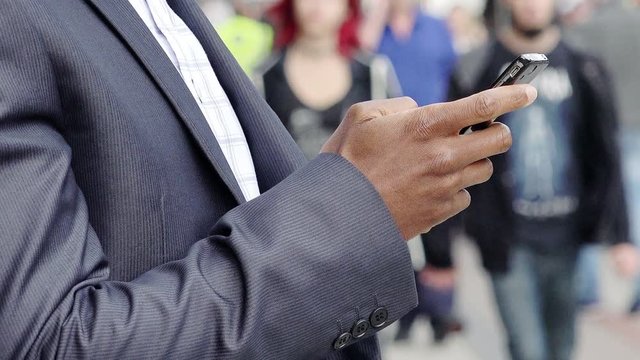 black businessman hands using smartphone with city street in background