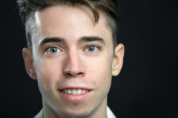 Handsome young man close portrait over black background