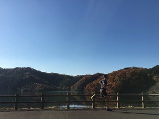 Runner running along path actoss top of dam besides reservoir