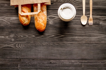 cup coffee and bread in paper bag on wooden background