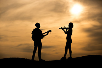 silhouette of musician with guitar play and violin player at sunset © ittipol