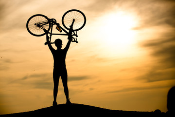 Silhouette of man with bicycle at sunset