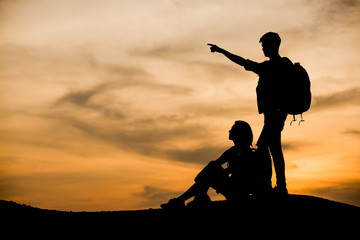 Silhouettes of two hikers with backpacks enjoying sunset