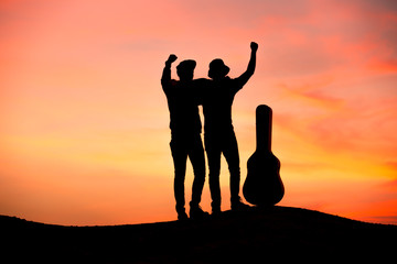 silhouette of musician with guitar at sunset