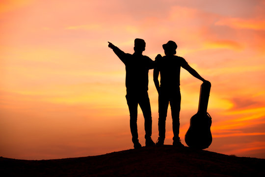 silhouette of musician with guitar at sunset