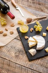 bottle of red wine, appetizers and corkscrew on wooden background