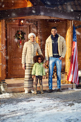 young family front wooden house on winter day