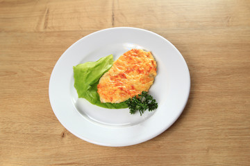 chicken in cheese and lettuce on a white plate on wooden backgro
